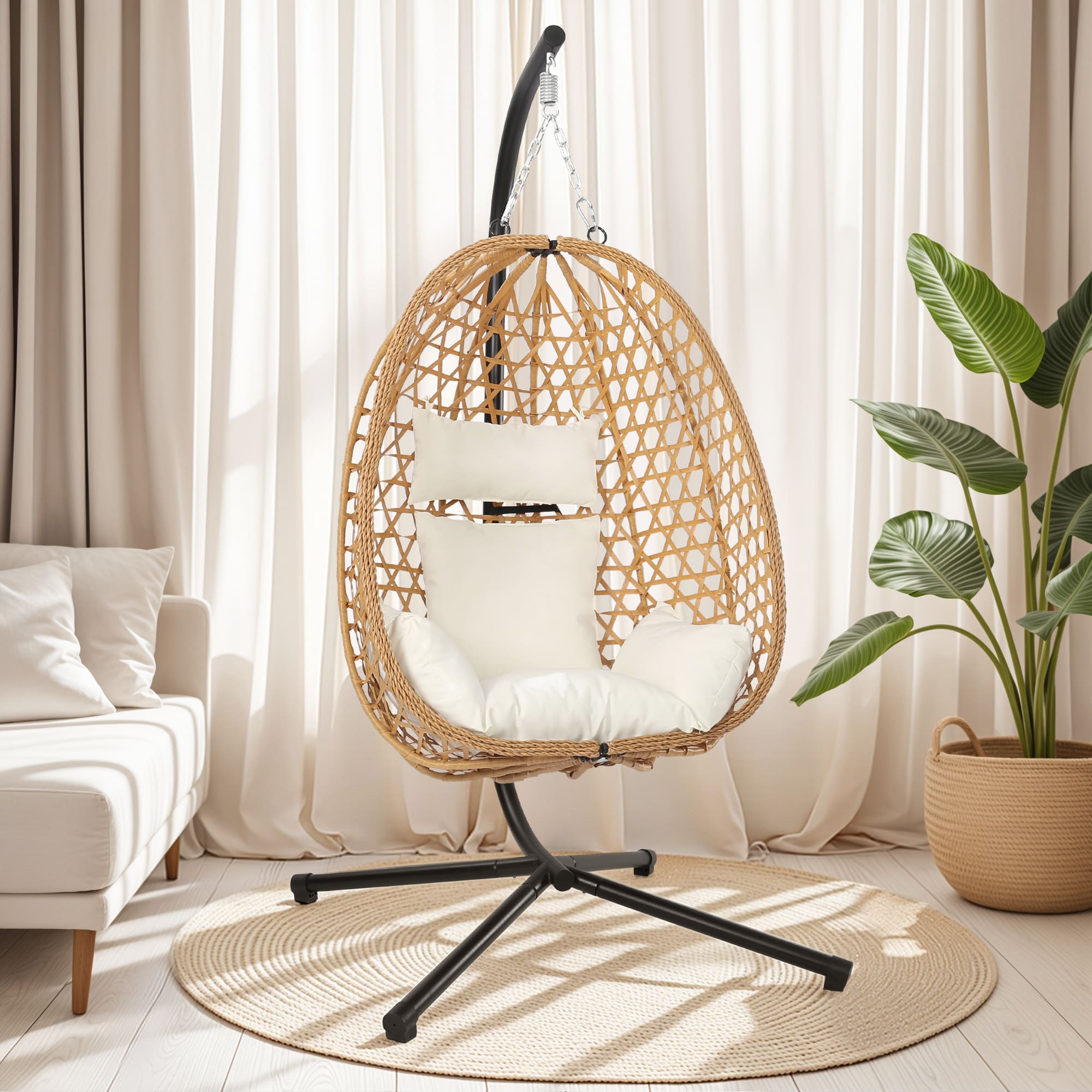 Woven egg-shaped hanging chair with white cushions in a cozy room with curtains and a plant.